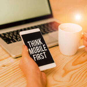 Person holding a smatphone with the words: "Think Mobile First" on the screen