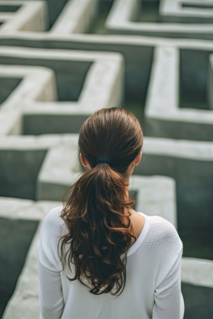 Woman viewed from behind facing a large, complex maze.